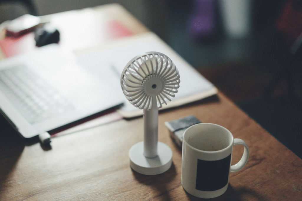 tiny-standing-fan-on-wood-desk-with-mug-and-papers